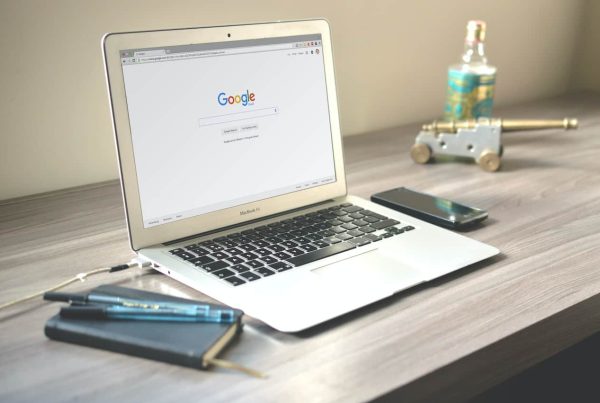 Open laptop displaying Google search page on a modern desk setup.